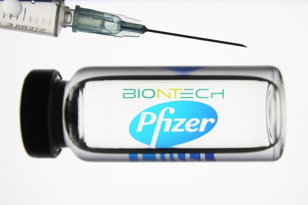 UKRAINE - 2020/11/24: In this photo illustration a medical syringe and a vial depicting fake coronavirus vaccine seen in front of the BioNTech German biotechnology company and Pfizer US multinational pharmaceutical corporation logos. (Photo Illustration by Pavlo Gonchar/SOPA Images/LightRocket via Getty Images)