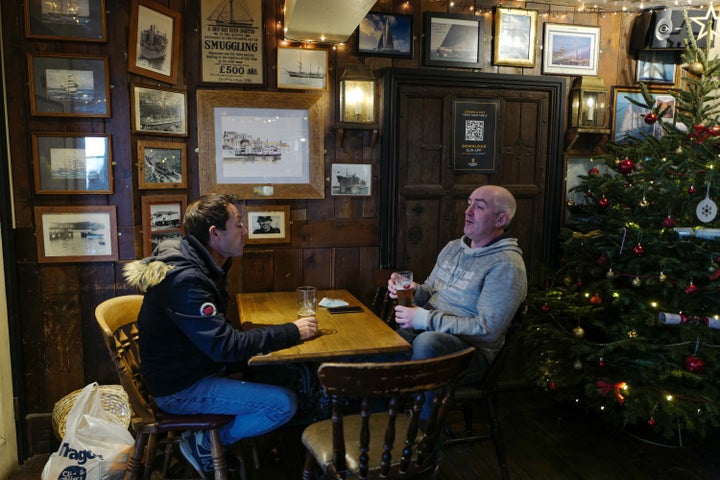 Customers enjoy their drinks next to a Christmas tree at the Chainlocker pub on December 2, 2020 in Falmouth, United Kingdom