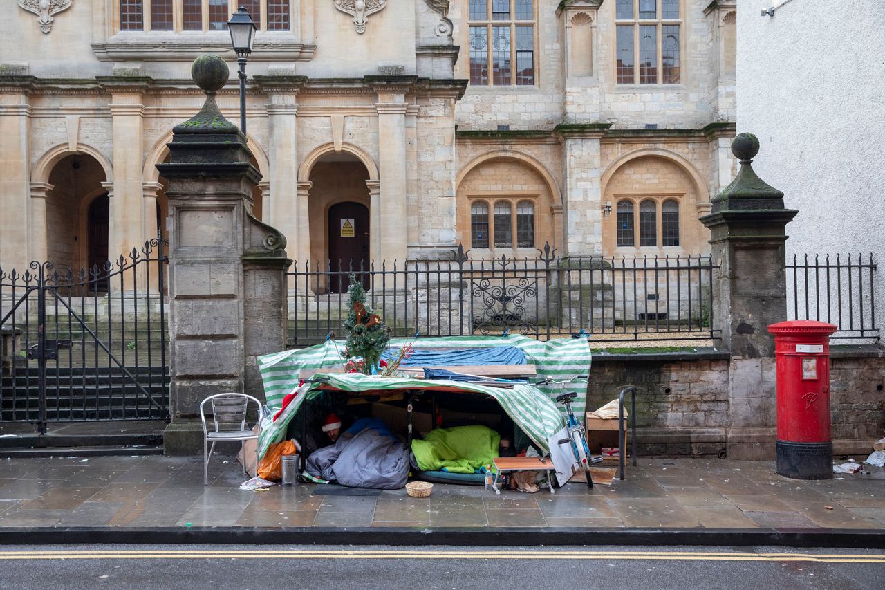 Two homeless men sleeping under a makeshift tent with festive decorations in Oxford, 2019. 