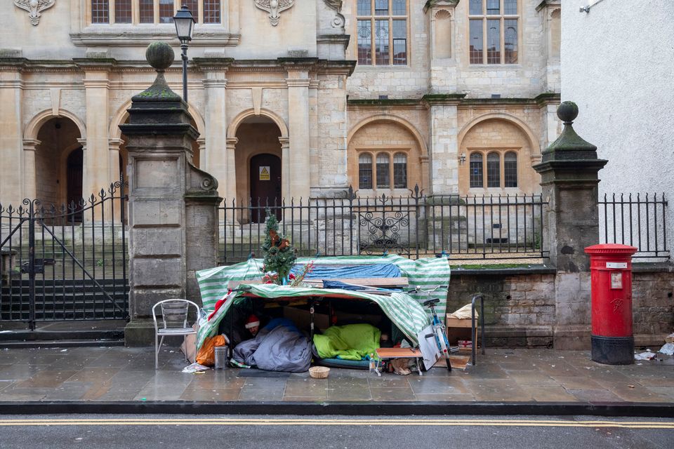 Two homeless men sleeping under a makeshift tent with festive decorations in Oxford, 2019. 