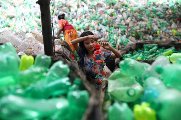 En marge de la signature d'un partenariat avec Suez, la Québécoise Loop Industries a déclaré être capable de produire 4,2 milliards de bouteilles de soda en plastique recyclé. Une jeune fille s'amuse avec un jouet en plastique trouvé dans une usine de recyclage à Dhaka, au Bangladesh, le 8 juillet 2019. Image d'illustration.