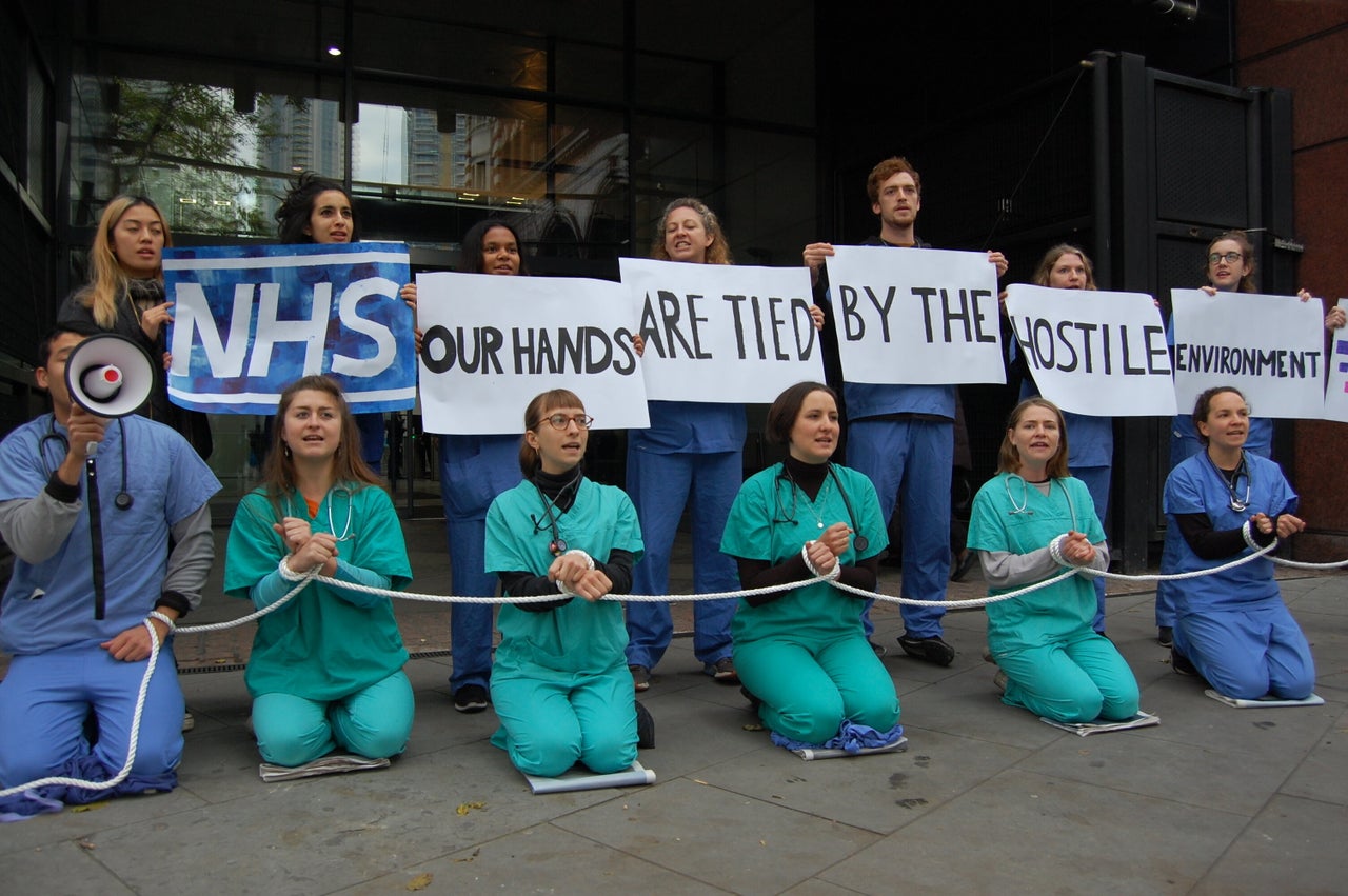 Medical staff protesting against the NHS' upfront charging policies, introduced as part of the hostile environment in 2017.