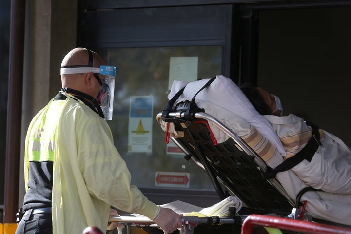 Employees of a stretcher service wear personal protective gear as they return a resident to Parkview Place personal care home, owned by Revera, in Winnipeg on Nov. 2, 2020.