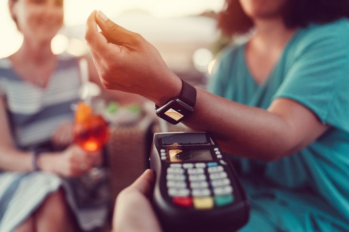 Young women in the bar paying contactless with smartwatch