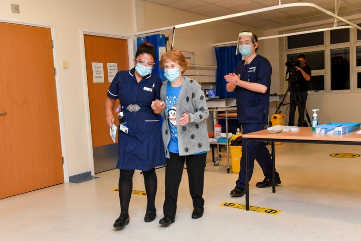 Margaret Keenan walks with nurse May Parsons after becoming the first person in the UK to receive the Pfizer-BioNTech COVID-19 vaccine, at University Hospital, Coventry, England, Tuesday Dec. 8, 2020.