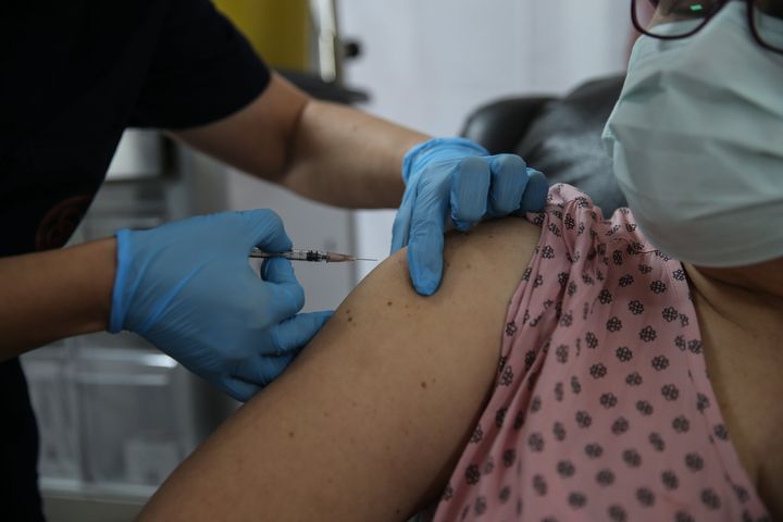 A health care worker injects a syringe of the phase three Pfizer/BioNTech vaccine trial into a volunteer at the Ankara Univer