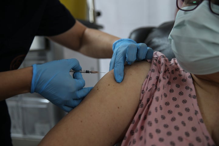 A health care worker injects a syringe of the phase three Pfizer/BioNTech vaccine trial into a volunteer at the Ankara University Ibni Sina Hospital in Ankara, Turkey.