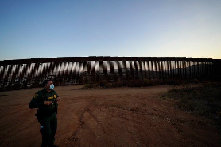 A U.S. Border Patrol agent looks out along newly replaced border wall sections near Tecate, California, back in September.