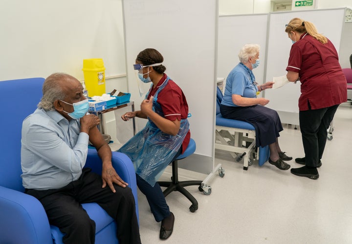 Care home worker Pillay Jagambrun (left), 61, receives the Pfizer-BioNTech Covid-19 vaccine in The Vaccination Hub at Croydon University Hospital, south London on Tuesday