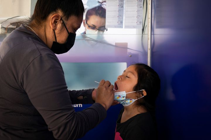 Claudia Campos swabs the mouth of her daughter, Katie Ramirez, at a testing site in Los Angeles on Dec. 9, 2020. 