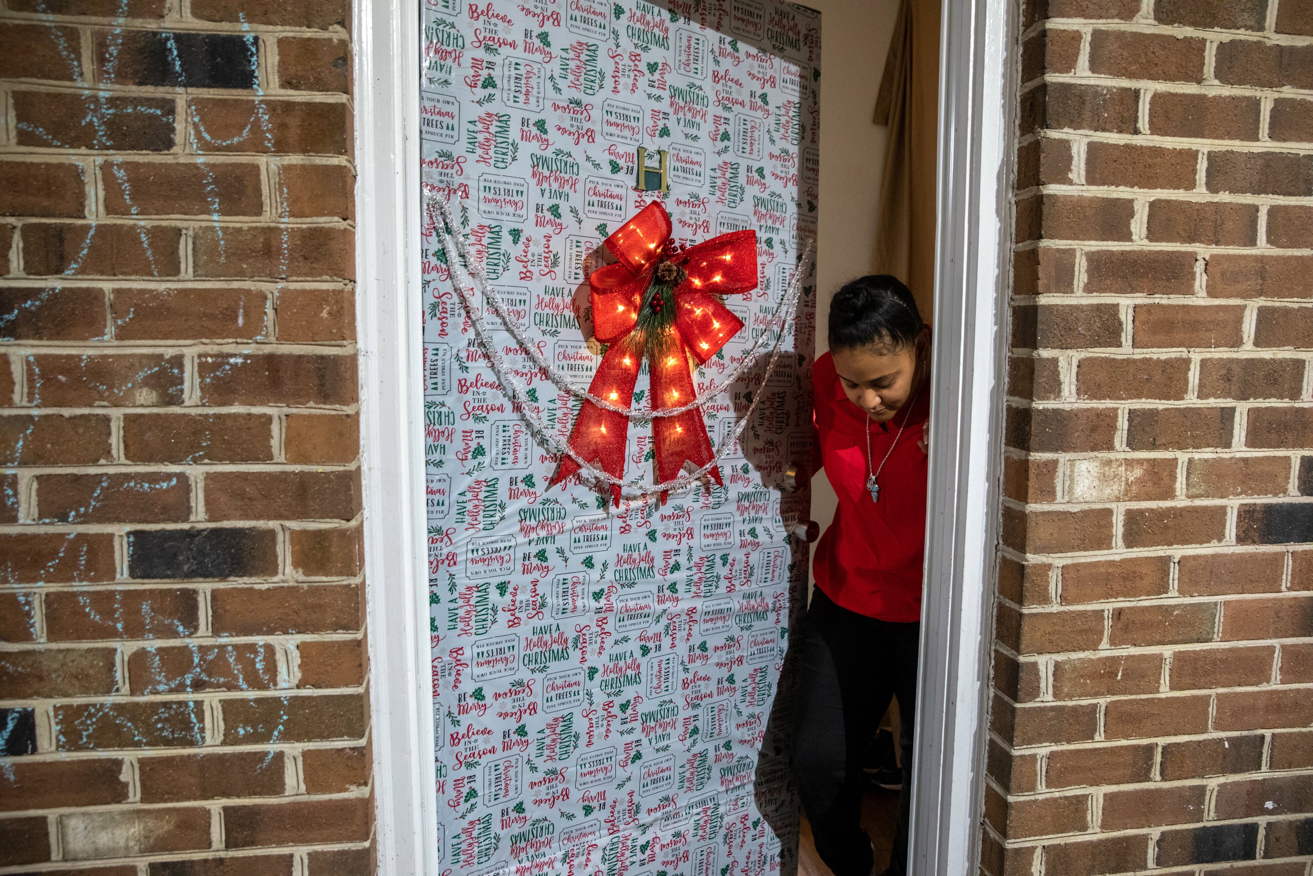Nawaal Walker stands at her decorated door in her home in Durham, North Carolina. Walker, a single mother of seven, is facing