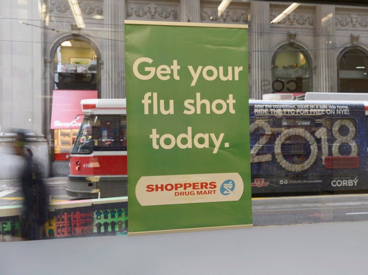 A man walks past a sign for flu shots in Toronto on Jan. 9, 2018.