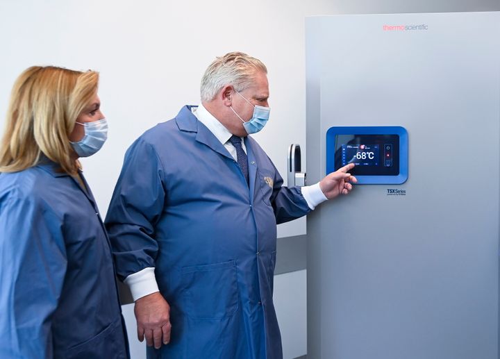 Ο πρωθυπουργός του Οντάριο Ντάγκ Φορντ, δεξιά και η υπουργός Υγείας του Οντάριο Κριστίν Έλιοτ εξετάζουν τους καταψύκτες πριν από τη διανομή εμβολίων COVID-19 στο Τορόντο.