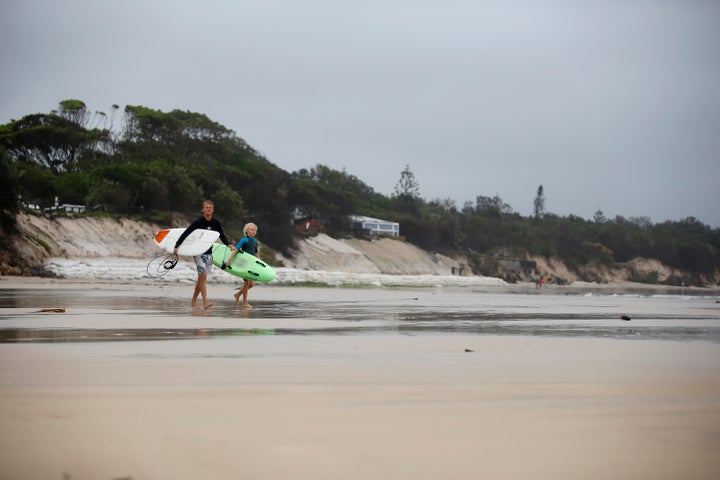 Surfers walk past the stretch of coastal areas seen disappeared due to erosion along the beach side, December 14, 2020 in Byron Bay, Australia.