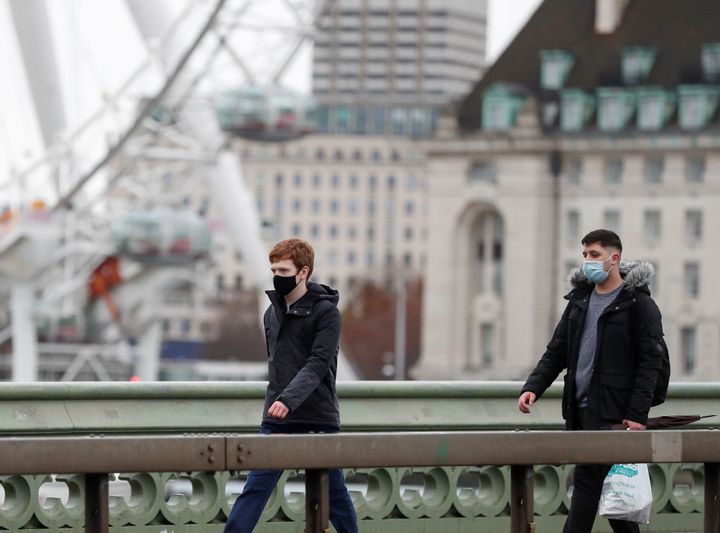 People wearing face masks walk along Westminster Bridge in central London on Sunday