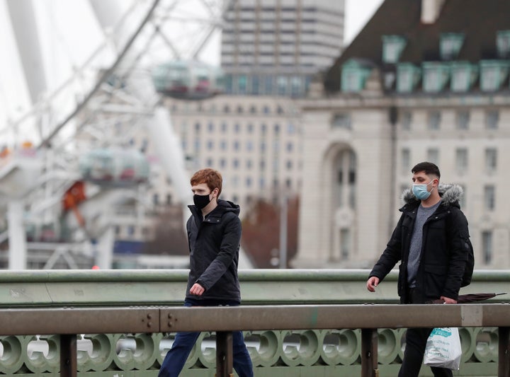 People wearing face masks walk along Westminster Bridge in central London on Sunday