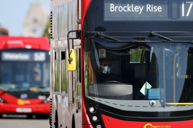 A bus driver wearing a face mask drives over Waterloo Bridge 