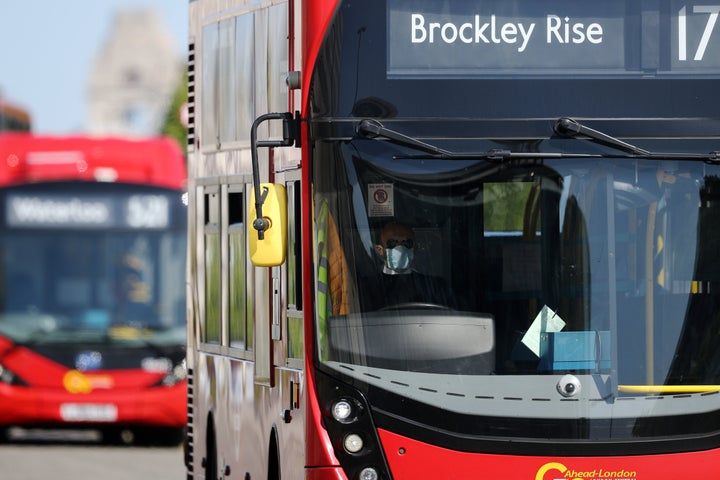 A bus driver wearing a face mask drives over Waterloo Bridge