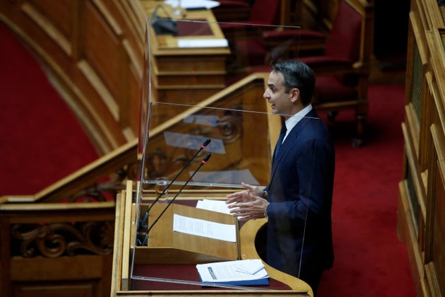 Greece's Prime Minister Kyriakos Mitsotakis speaks, behind a protective plastic barrier to protect against coronavirus during a debate for a new environmental law at the Greek Parliament in Athens, Tuesday, May 5, 2020. Environmental groups in Greece are urging the public to join a campaign against plans by the center-right government to overhaul off-shore oil-and-gas exploration rules which authorities argue will help the country end its dependency on coal. (AP Photo/Thanassis Stavrakis)
