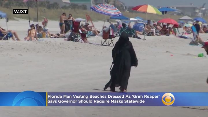 Daniel Uhlfelder walks along a beach in a Grim Reaper outfit in hopes of encouraging people to stay home to prevent COVID-19 from spreading.