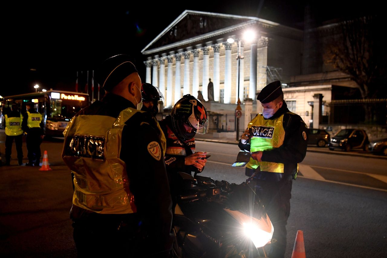 French police check the permission to move of a motorcyclist on December 15, 2020 in Paris, as a new 8 pm to 6 am curfew is implemented in France to avoid a third wave of coronavirus infections.