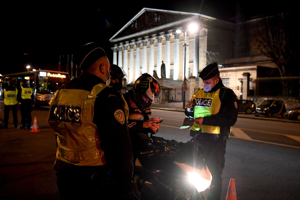 French police check the permission of a motorcyclist to travel on Dec. 15 in Paris. A new curfew between 8 p.m. to 6 a.m. was