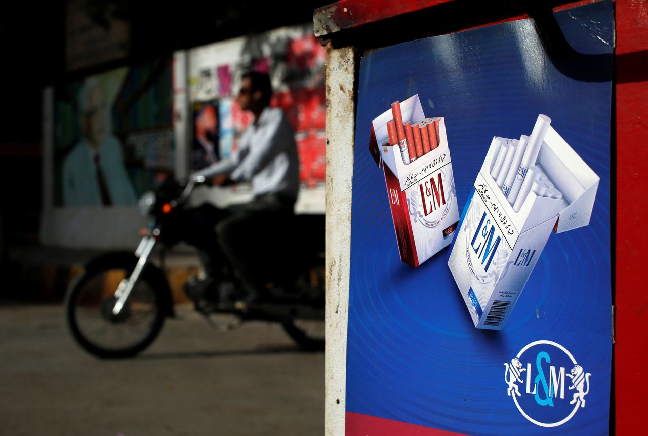 A commuter rides his bike past an advertisement for L&M cigarettes, a Philip Morris International brand, at a kiosk along a road in Karachi, Pakistan in May 2018.