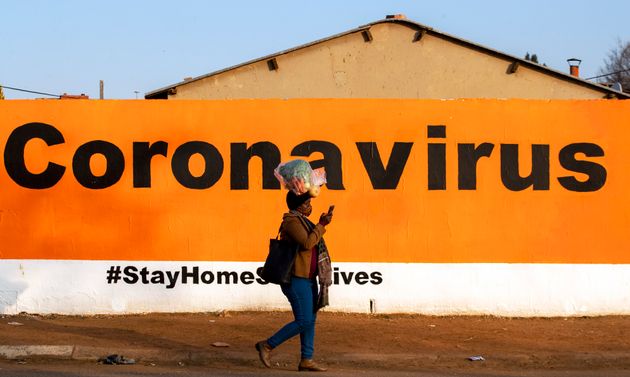 Una mujer pasa ante un cartel de alerta sobre el coronavirus en Johannesburgo, en pasado