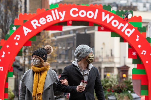 Two people wearing face masks walk beneath an archway in Covent Garden in London, which has moved into the highest tier of coronavirus restrictions as a result of soaring case rates.