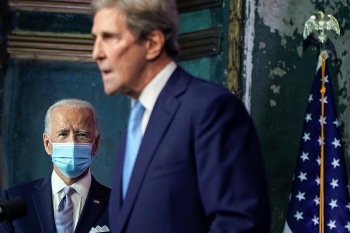 President-elect Joe Biden listens as former Secretary of State John Kerry, his pick for special presidential envoy for climate, speaks at a press conference announcing his selection for the post.