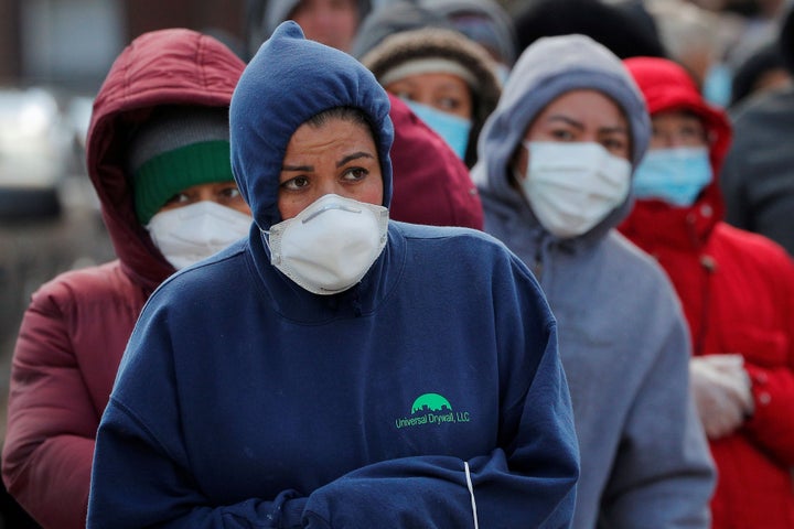 People wait in a line that wraps around the block in Chelsea, Massachusetts, for a pop-up food pantry amid the pandemic on April 17.