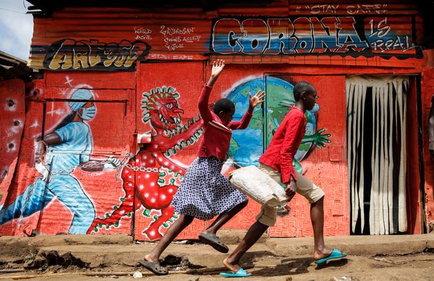 Unos niños corren ante un mural que alerta de los riesgos del coronavirus, el pasado junio, en...