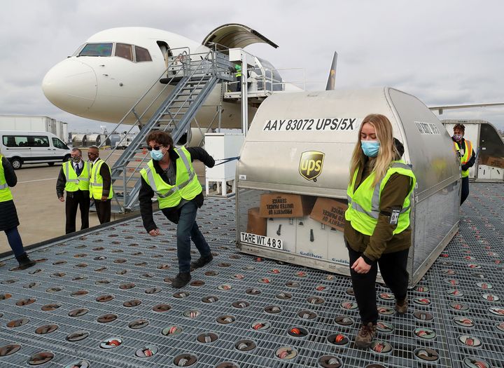 13 Δεκεμβρίου. Υπάλληλοι της εταιρείας UPS μεταφέρουν κοντέινερ με εμβόλια της Pfizer για COVID-19 στο αεροδρόμιο της Λούισβιλv "Μοχάμεντ Άλι" στο Κεντάκι των ΗΠΑ. Michael Clevenger/Pool via REUTERS