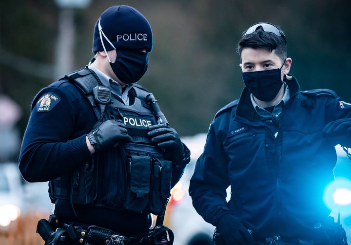 RCMP officers wearing face masks to curb the spread of COVID-19 stand by as protesters opposed to the Trans Mountain pipeline expansion block rail lines in Burnaby, B.C., on Nov. 27, 2020. 