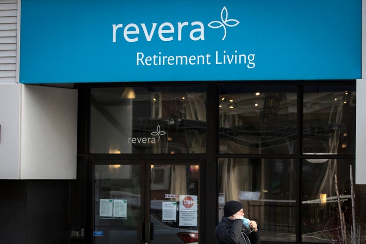 A person wears a mask while walking past Revera Retirement Living residence in Kingston, Ont. on Dec. 8, 2020.