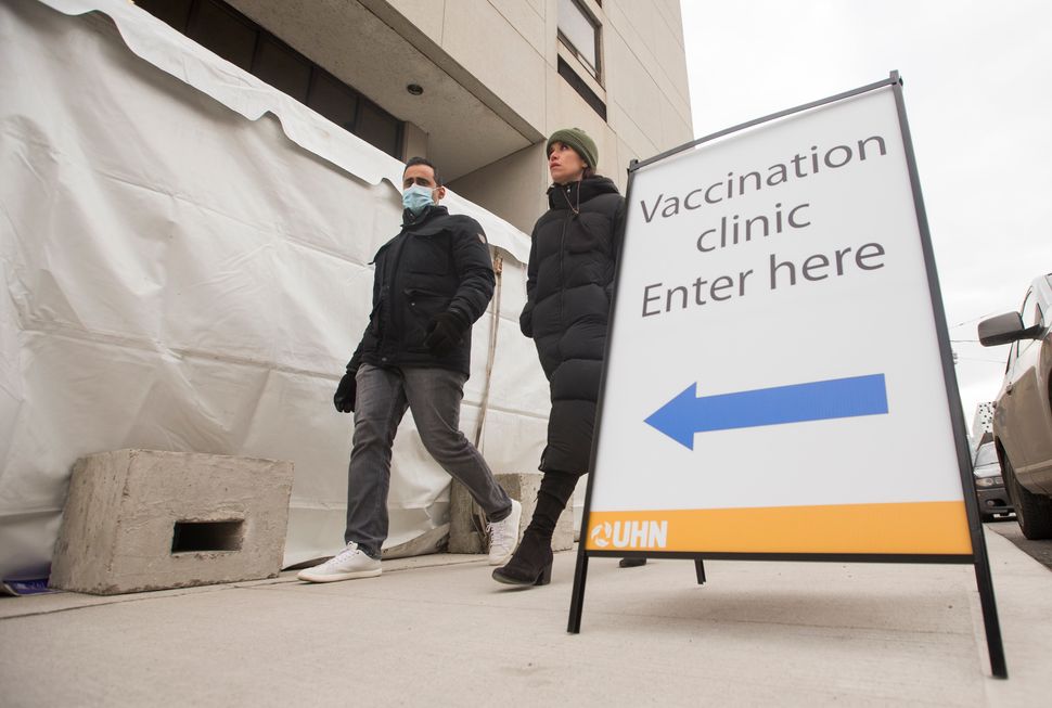 Two people walk past the UHN's Vaccination Pilot injection site set up to administer the COVID-19 vaccine on Dec. 15, 2020.