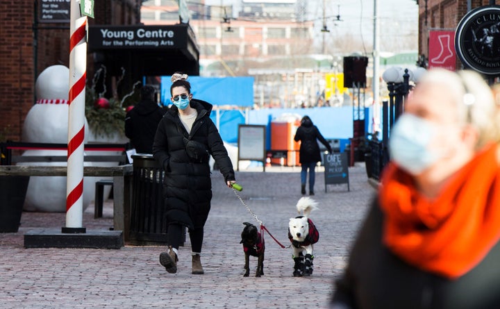 A woman wearing a face mask walks dogs on a street in Toronto, Canada, on Dec. 3, 2020.