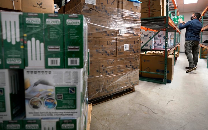 Ray Bellia stocks shelves with personal protective gloves, used by medical and law enforcement professionals, while unpacking