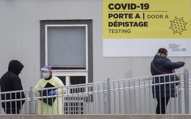 A healthcare worker talks to people as they wait to be tested for COVID-19 at a testing clinic in Montreal...