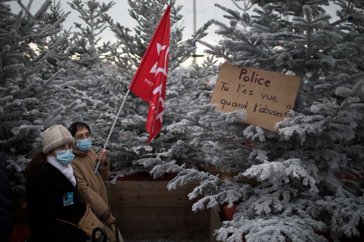 5 Δεκεμβρίου 2020 Παρίσι Διαδηλωτές περνούν μπροστά από ένα χριστουγιεννάτικο δέντρο στο οποίο έχει τοποθετηθεί μια ταμπέλα που γράφει: "Αστυνομία μπορείς να δεις τα λάθη που διαπράτεις " Νωρίτερα είχαν προηγηθεί συγκρούσεις με διαδηλωτές όπου αρκετά αυτοκίνητα και άλλη περιουσία καταστράφηκε.