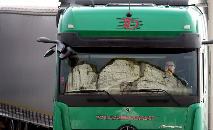 The White Cliffs are reflected in the windscreen of a lorry whilst the driver sits his cab and queues to enter the port of Dover.