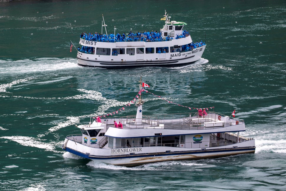 Le bateau touristique américain Maid of the Mist, dont le taux d'occupation est limité à 50 % en vertu des régulations de l'état de New York, croise un vaisseau canadien dont l'occupation est limitée à six passagers par les régulations de l'Ontario. Chutes du Niagara, Ontario, Canada, 21 juillet.