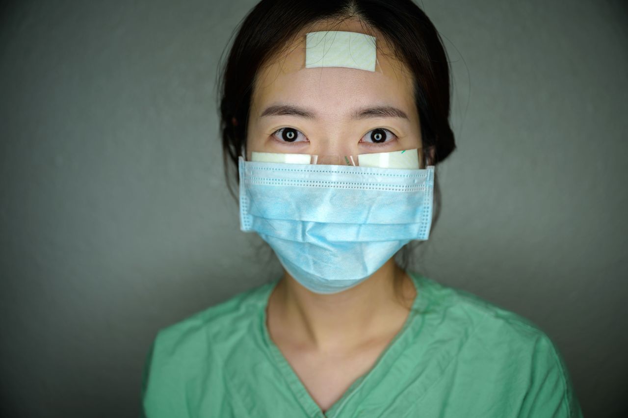 Nurse Yun Na-yong poses during a break between shifts at Keimyung University hospital in Daegu, South Korea, on March 12. Nurses caring for coronavirus patients wear bandages on their faces to help prevent painful sores while wearing full-body protective suits for hours on end.