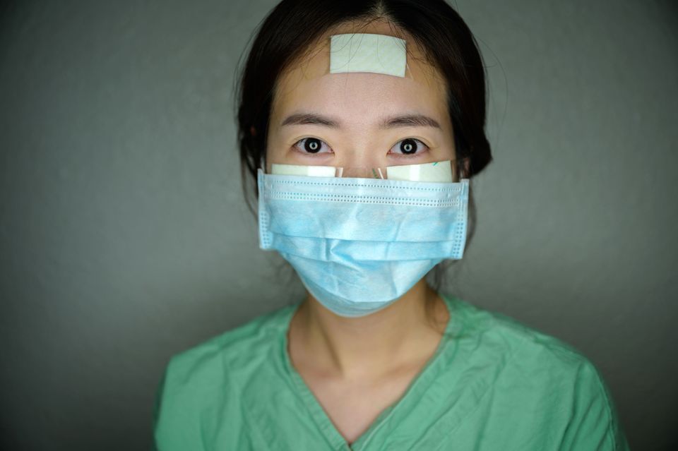 Nurse Yun Na-yong poses during a break between shifts at Keimyung University hospital in Daegu, South Korea, on March 12. Nurses caring for coronavirus patients wear bandages on their faces to help prevent painful sores while wearing full-body protective suits for hours on end.