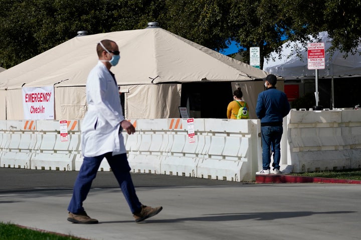 A medical worker passes a medical tent outside the emergency room at UCI Medical Center in Irvine, Calif. on Thursday. California is desperately searching for nurses, doctors and other medical staff to meet demands.