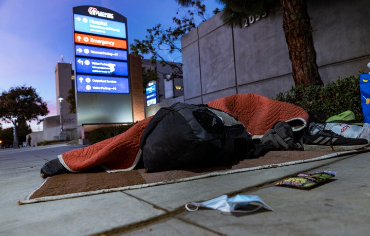 A homeless person sleeps outside the Los Angeles County + USC Medical Center hospital entrance in Los Angeles on Wednesday. H