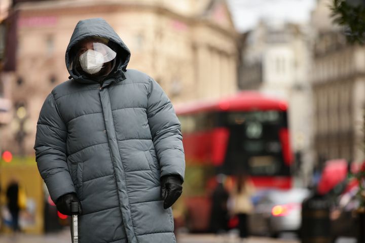 A man wearing a face mask and face shield waits at a pedestrian crossing on Regent Street in London, England, on Dec. 21, 2020. 