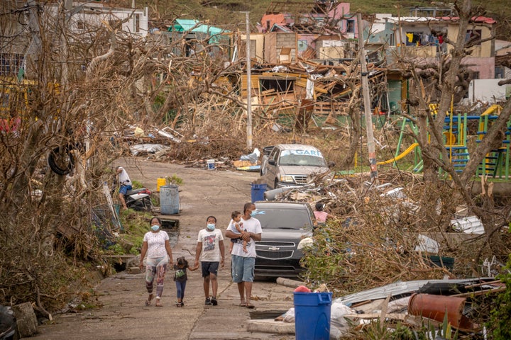 A family walks amid destruction on Nov. 22 in Providencia, Colombia, which was hit by Hurricane Iota as a Category 5 storm, t