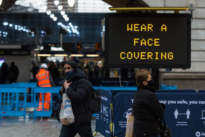 Pedestrians walk past a "wear a face covering" message displayed outside Victoria station this week