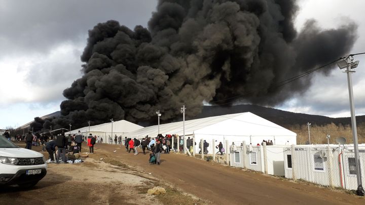 Refugees leave a camp as a fire burns, near the northwestern village of Lipa, Bihac region, on December 23, 2020. - A refugee camp in Bosnia criticised for its bleak conditions was destroyed in a fire on December 23 police said, as the country faces a repeat crisis over where to shelter migrants during winter. There were no casualties or injuries, but the infrastructure of the site near the northwestern village of Lipa was destroyed, police spokesperson Ale Siljdedic told AFP. (Photo by STR / AFP) (Photo by STR/AFP via Getty Images)